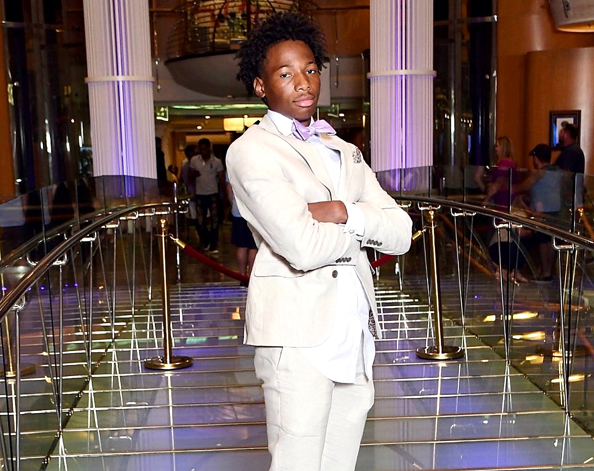 Karmelo Anthony in cream suit at formal event, arms crossed, poised and confident