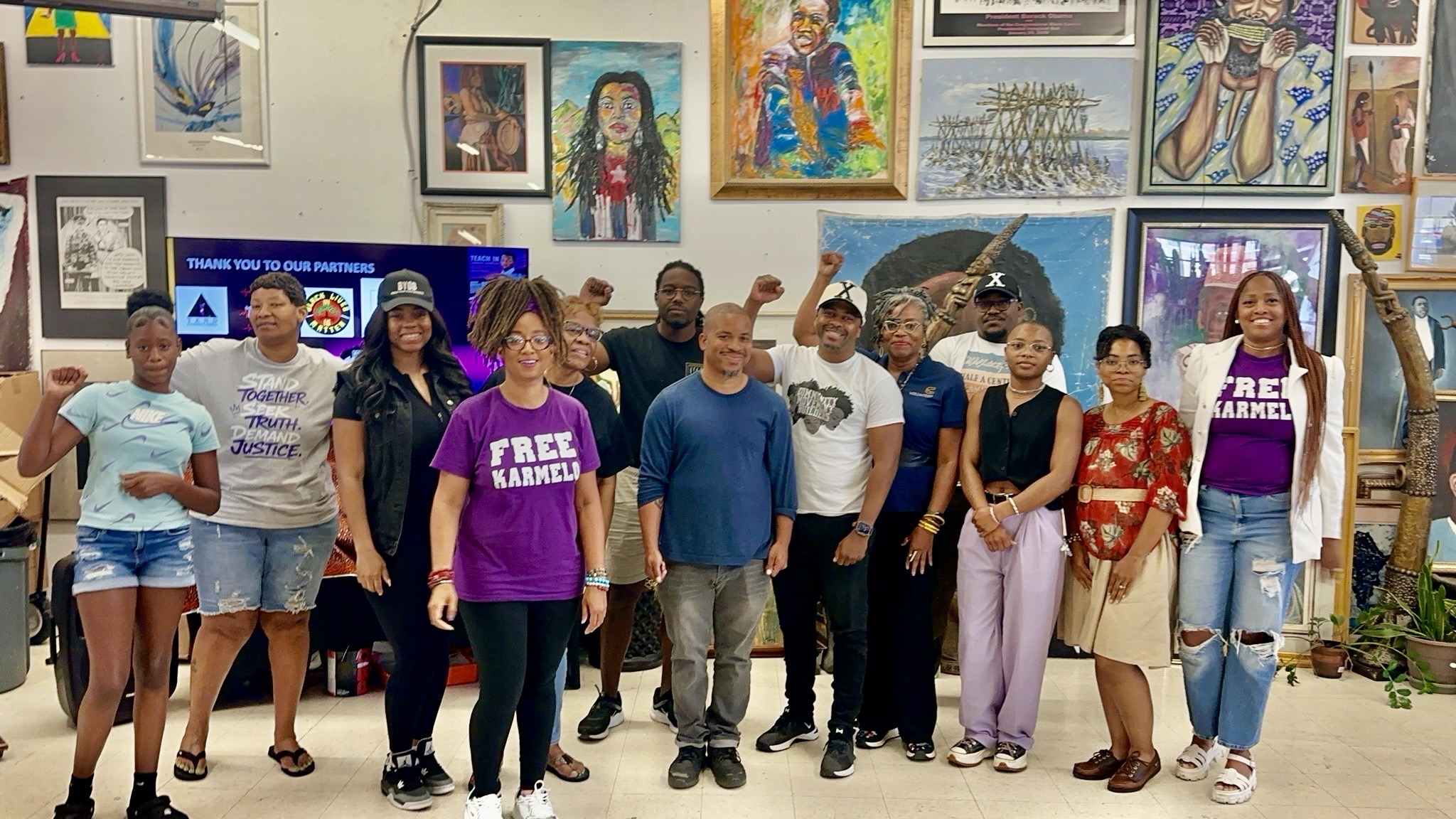 Organizers and supporters at the first Karmelo Teach-In — FREE KARMELO shirts, fists raised — Pan African Connection Bookstore, Dallas, August 2026.